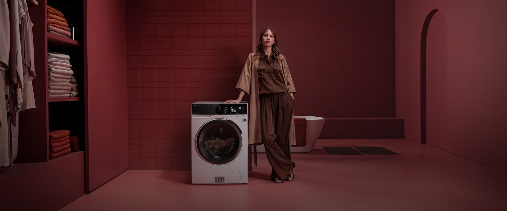 En kvinde der står ved siden af en fritstående vaske-tørremaskine i et rødt rum.